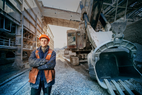 Worker,In,A,Helmet,Stands,Near,A,Big,Excavator,Crossed